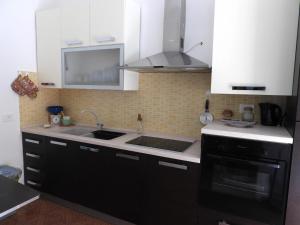 a kitchen with white cabinets and a sink and a stove at Doribella Holiday House in Pollina +8 photos