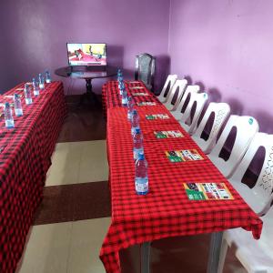 a long table with red table cloth and white chairs at Crown Accommodation Narok in Narok