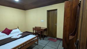 a bedroom with a bed and a desk and a door at Kabani Villa in Mananthavady