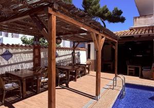 a wooden pergola with tables and chairs on a patio at El Cortijo Escana in Es Cana