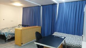 a bedroom with blue curtains and a bed and a desk at Cozy studio apartment with 2 beds and kitchen in Audun-le-Tiche