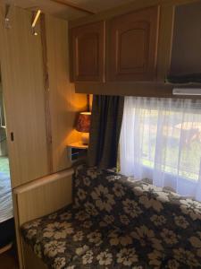 a bed in an rv with a window at Camping Rogowo in Mrzeżyno
