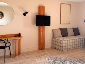 a living room with a couch and a tv on a wall at Hotel Restaurant Auberge du Barrez Logis in Mur-de-Barrez