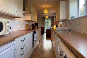 a large kitchen with white cabinets and a sink at Walled garden cottage in Hassocks