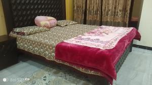 a bed with a red blanket and pillows on it at BHURBAN MOUNTAIN VIEW APARTMENTs in Murree +11 photos