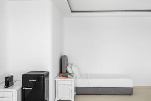 a white room with a bed and a refrigerator at Neraé Santorini in Imerovigli