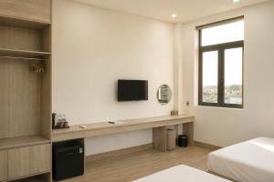 a bedroom with a desk with a tv on the wall at Khách sạn New Star 2 in Thiện Ngôn