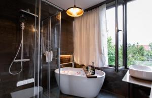 a bathroom with a tub and a shower and a sink at AUTOGRAPH Kutaisi in Kutaisi +44 photos