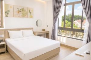 a white bedroom with a bed and a window at Khách sạn New Star 2 in Thiện Ngôn