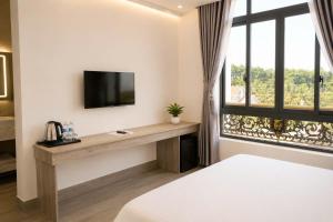 a bedroom with a desk with a tv and a window at Khách sạn New Star 2 in Thiện Ngôn