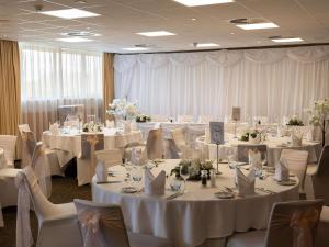 a room filled with tables and chairs with white linens at Novotel Milton Keynes in Milton Keynes +110 photos