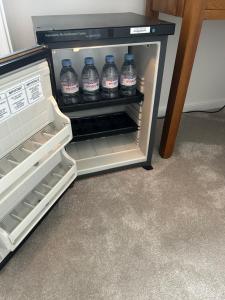 an open refrigerator with bottles of water in it at Windsor Gate Room,Windsor in Dorney