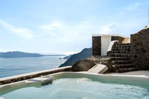 a hot tub with the ocean in the background at Neraé Santorini in Imerovigli