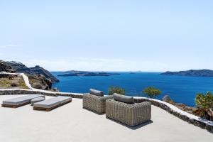 a patio with chairs and a view of the ocean at Neraé Santorini in Imerovigli