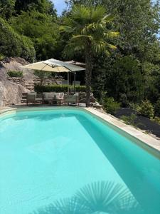 a large blue swimming pool with an umbrella and chairs at Rustico Villa Antonia with seaview and pool in Bieno