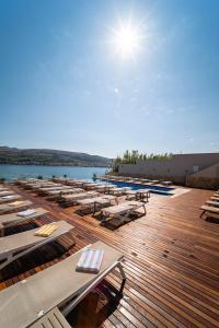 a row of lounge chairs and tables on a deck at Hotel Plaza in Pag