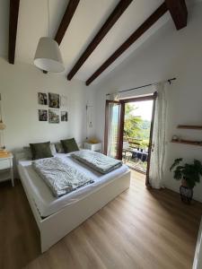a white bedroom with a bed and a sliding glass door at Rustico Villa Antonia with seaview and pool in Bieno +57 photos