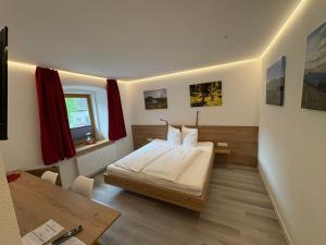 a bedroom with a bed and a desk and a window at Frühstücks-Radpension Taurer-Thoman in Dellach im Drautal
