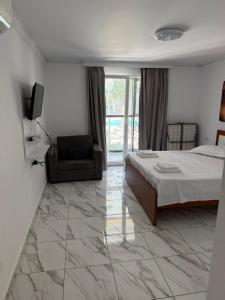 a bedroom with a bed and a tv and a chair at Elois Apartments in Shëngjin