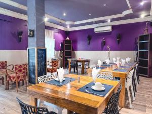 a dining room with wooden tables and purple walls at Le Lodge des Almadies in Dakar