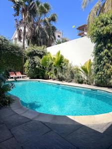 a swimming pool in front of a house with palm trees at Le Lodge des Almadies in Dakar