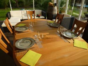 a wooden table with plates and wine glasses on it at Chambre D'hôtes Indépendante in Pessac