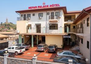 a hotel with cars parked in a parking lot at NEFAR PALACE HOTEL Plc in Bafoussam