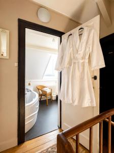 a white shirt hanging on the door of a bathroom at La Cour Du Puits Chambre Rooibos in Cormeilles