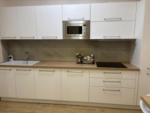a kitchen with white cabinets and a sink and a microwave at The Superhost - Marekiaro in Crotone