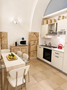 a kitchen with white cabinets and a table and chairs at Ulìa - Stone house tra borgo antico e mare in Giovinazzo