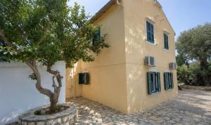 a building with a tree in front of it at Nature's Nook Paxos in Vlachopoulátika