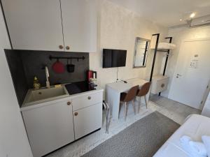 a kitchen with white cabinets and a sink and a table at Studio Apartments - Pula city center in Pula