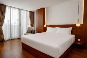a bedroom with a large white bed and a window at The Scenic Hotel in Phnom Penh