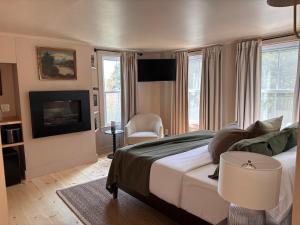 a bedroom with a large bed and a television at Hideaway Inn Maine in Camden