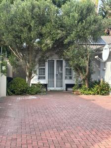 a house with trees in front of a brick driveway at Sharwood Place in Port Elizabeth