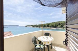 a balcony with a table and chairs and a view of the water at Apartment Mirni by the sea in Prvić Luka