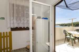 a white refrigerator in a room with a balcony at Apartment Mirni by the sea in Prvić Luka