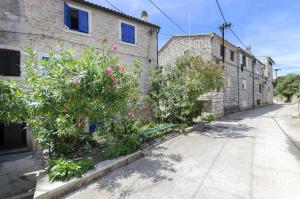a building with trees and flowers next to a street at Apartment Mirni by the sea in Prvić Luka