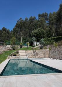 a swimming pool in a yard with a stone wall at Caza de Cima de Villa in Penafiel