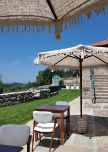 a table and two chairs and an umbrella at Caza de Cima de Villa in Penafiel