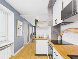 a kitchen with white cabinets and a blue wall at Radość z Marzeń in Suwałki