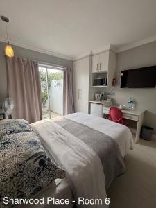 a bedroom with a bed and a desk and a kitchen at Sharwood Place in Port Elizabeth