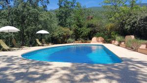 a swimming pool in a yard with chairs and an umbrella at Hotel Rural El Camino in Candeleda