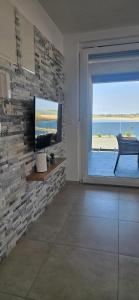 a living room with a tv and a brick wall at APARTMANI SUNSIDE NIN in Nin