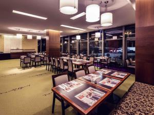 a restaurant with wooden tables and chairs and windows at Hotel Mercure Toruń Centrum in Toruń