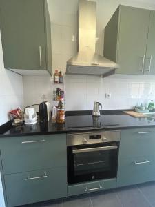 a kitchen with gray cabinets and a stove top oven at Quarto 15 min de Lisboa in Amadora