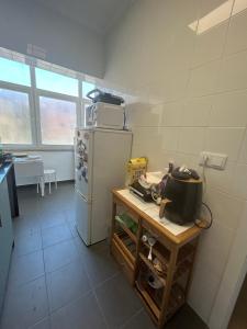 a kitchen with a white refrigerator and a table at Quarto 15 min de Lisboa in Amadora