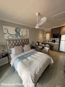 a bedroom with a large bed and a kitchen at Sharwood Place in Port Elizabeth