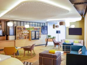 a living room with couches and chairs and a tv at Mercure Nantes Centre Gare in Nantes