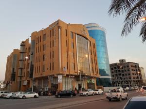 a building with cars parked in a parking lot at Travellerinn Serviced Apartment in Al Khobar